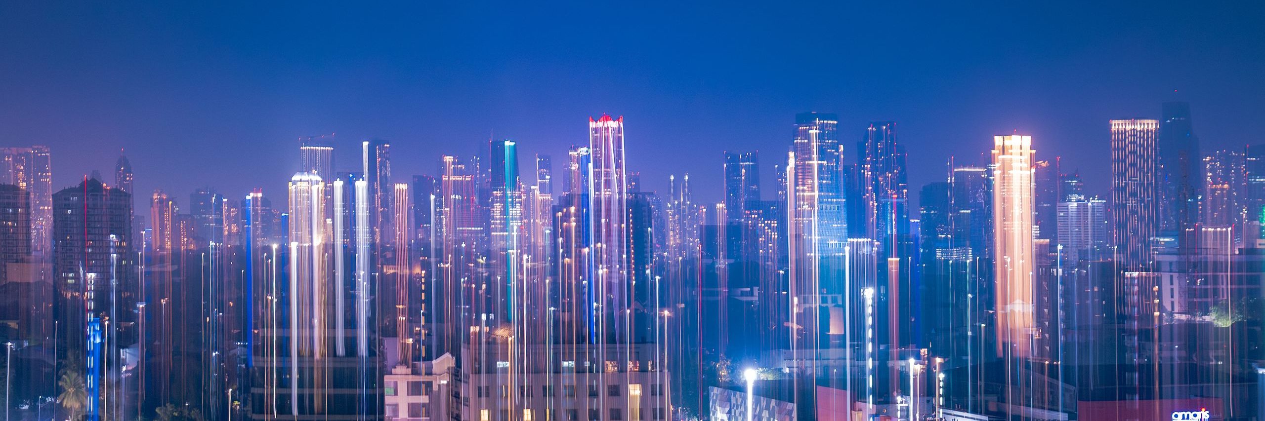 A dynamic capture of Jakarta's skyline at night with vibrant neon light streaks and city lights.
